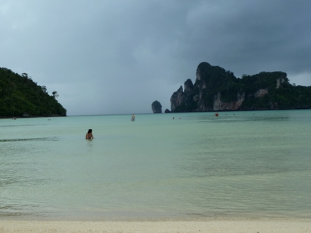The crystal clear water of Ao Loh Dalam bay shimmers under the heavy skies over Ko Phi Phi Don, Thailand.