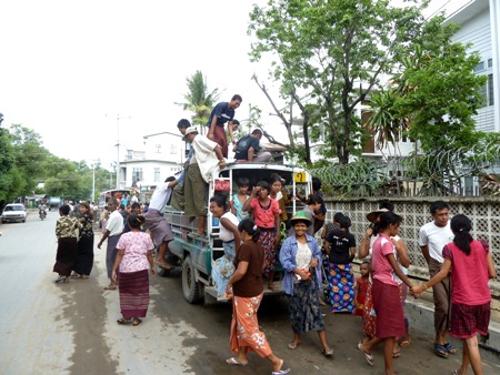 A horde of locals bails off of a standardly overloaded pickup in Mandalay, Myanmar. A horde of locals bails off of a standardly overloaded pickup in Mandalay, Myanmar.