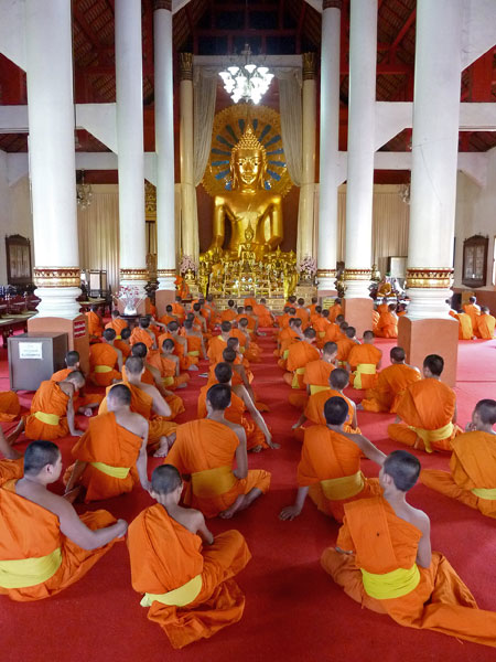 Novice Buddhist monks engage in a prayer ceremony at Wat Phra Singh in Chiang Mai, Thailand.