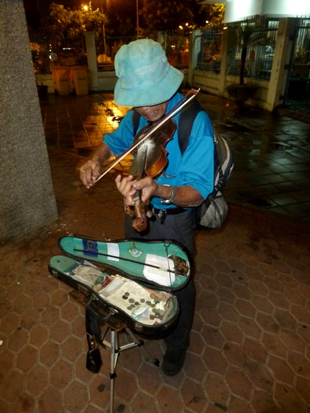 A violinist saws away near the Sathorn stop on the Chao Phraya river in Bangkok, Thailand.