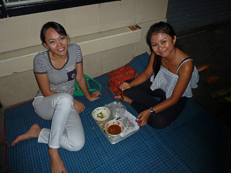Thai girls eat for fun on the sidewalk in Banglamphu, Bangkok, Thailand.
