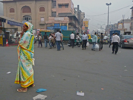 A woman in a color-soaked sari stands on Chandni Chowk in Old Delhi, India.