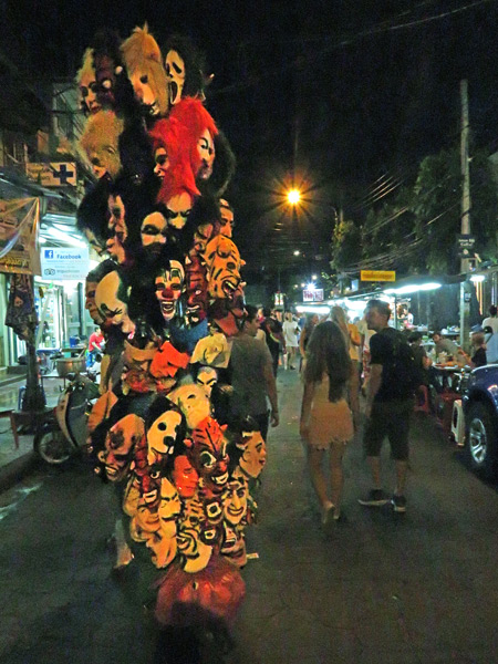 A man hauls a tall, skinny cart full of masks down Thanon Rambuttri in Bangkok, Thailand.