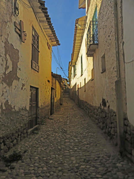 A sunlit cobblestone back lane in Cuzco, Peru.
