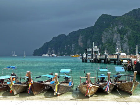 A row of longtail boats all lined up next to the pier on Ao Ton Sai Bay at Ko Phi Phi Don, Thailand.