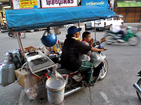 A tuk-tuk food cart pulls away in Phuket Town, Thailand.
