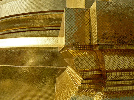 Close-up of the gold tiles of the Phra Siratana Chedi glowing in the afternoon sun at the Temple of the Emerald Buddha in Bangkok, Thailand.