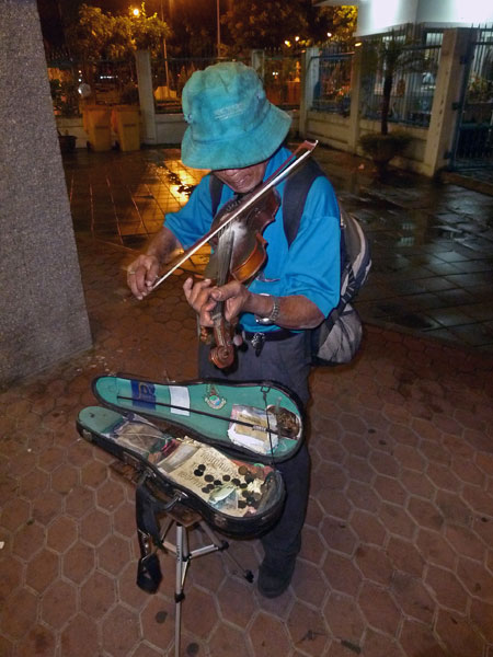 A violinist saws away near the Sathorn stop on the Chao Phraya river in Bangkok, Thailand.