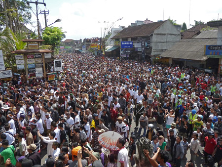 A vast river of humanity veers from the street into the royal cremation ceremony at Pura Dalem Puri in Ubud, Bali, Indonesia.