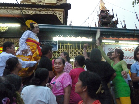 A nat kadaw clowns around outside the main Buddhist temple at the Nat Pwe in Taungbyone, Myanmar.