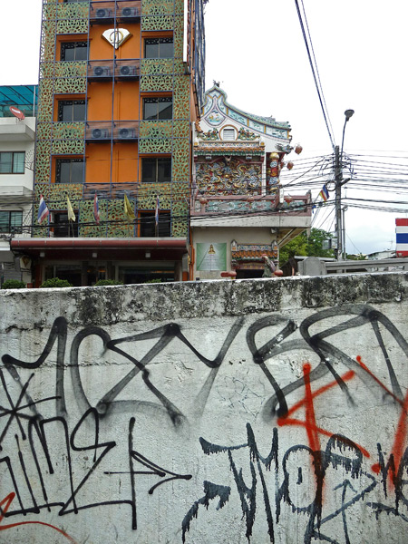 A high-rise, a Chinese Buddhist temple and graffiti peacefully co-exist in Banglamphu, Bangkok, Thailand.