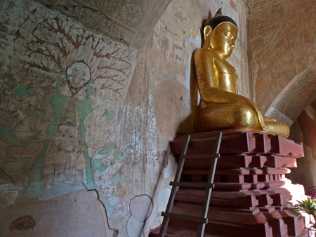 Paintings on stucco walls accompany Buddha inside Dhammayangyi Pahto temple in Bagan, Myanmar.
