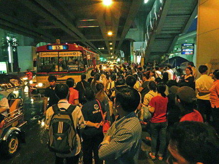 A unusually thick crowd at 10:30 pm waits for various buses at Siam in Bangkok, Thailand.