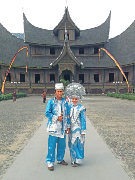 A couple tries on traditional Minangkabau costumes in front of Pagarayung Palace near Batu Sangkar, Sumatra, Indonesia.